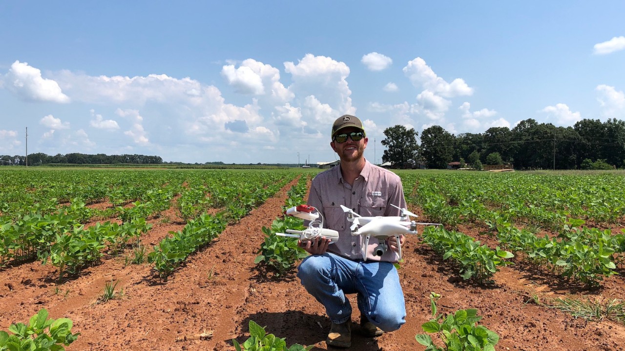 A man in a field holding a drone.